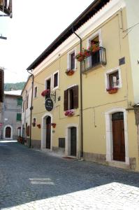 a yellow building with flower boxes on a street at Bed and Breakfast Via Della Piazza in Pescasseroli