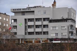 a white building with a green cross on it at Hande Hotel in Mustafakemalpaşa
