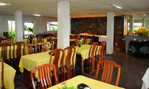 a dining room with tables and chairs with yellow table cloth at Viver Hotel Fazenda in Moreno