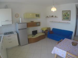 cocina y sala de estar con sofá azul y mesa en President Frontemare - Agenzia Cocal, en Caorle