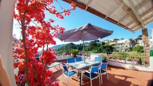 un tavolo e sedie su un balcone con fiori rossi di Villa La Favola a Ischia