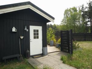 un capanno nero con una porta bianca sul ponte di Ängshyddan B&B a Yngsjö