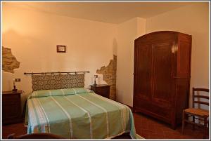 1 dormitorio con 1 cama y armario de madera en Agriturismo Poggio Macinaio, en Roccastrada