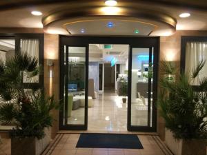 hol budynku ze szklanymi drzwiami i roślinami w obiekcie Hotel Adele w mieście Bellaria-Igea Marina