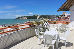 a patio with white tables and chairs and the ocean at Marambaia Apart Hotel in Natal