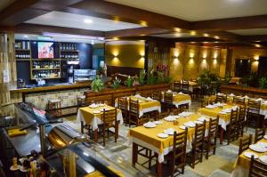 a restaurant with yellow tables and chairs and a bar at Rohedama Hotel in Guaratinguetá