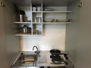 a kitchen with a sink and a stove and shelves at BusinessInn.de Aparthotel Bremerhaven in Bremerhaven