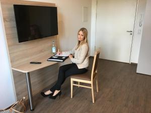 BusinessInn.de Aparthotel Bremerhaven في برمرهافن: امرأة تجلس في مكتب في غرفة