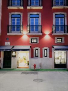 a red building with windows and a fire hydrant in front at Hotel Riverside Alfama in Lisbon