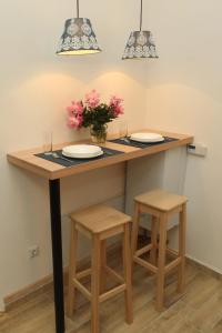 Blue Box Apartment في بلغراد: جزيرة مطبخ مع كرسيين وطاولة مع ورد