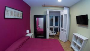 a purple bedroom with a bed and a tv at Ocho Home Apartamentos in Zamora