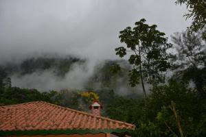 een huis met een rood dak en een boom en wolken bij Pousada Ribeirao da Floresta in Lumiar