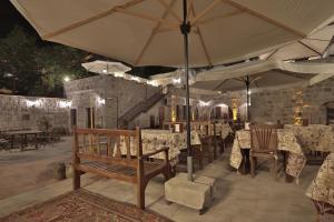 a restaurant with a bench and tables with umbrellas at Guzide Cave Hotel in Göreme