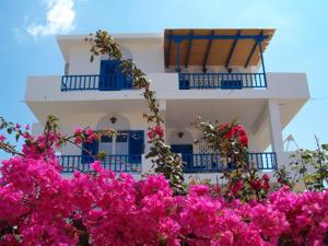 um edifício branco com varandas azuis e flores cor-de-rosa em Villa Niki em Serifos Chora