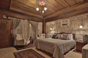 a bedroom with a bed and a stone wall at Guzide Cave Hotel in Göreme