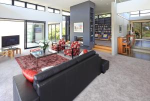 a living room with a black couch and red chairs at Blackwood Retreat in Oneroa