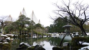 a garden with a pond with a bridge in it at Sennichi House in Kanazawa