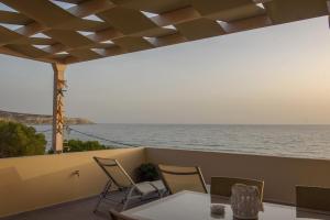 a table and chairs on a balcony with a view of the ocean at Pelini in Kalamaki Heraklion
