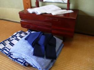 een dressoir met een stapel kleren op de vloer bij Marumo Ryokan in Takashima