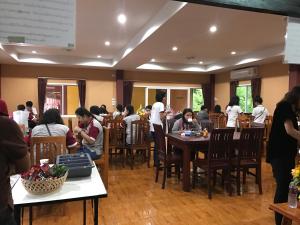 um grupo de pessoas sentadas em mesas em um restaurante em Khwanruen Fishing Resort em Ban Chang