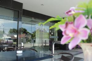 a table with chairs and a vase with pink flowers at Salsa Resort Langkawi By Casa Loma in Pantai Cenang