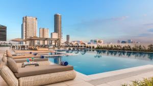 a swimming pool with lounge chairs and a city skyline at Seda Vertis North in Manila