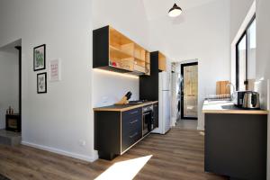 a kitchen with white walls and black cabinets at Margaret River Bungalow-1-street - pet friendly in Margaret River Town
