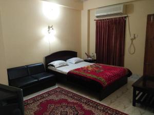 a bedroom with a bed and a chair and a couch at Hotel Plaza in Bāndarban