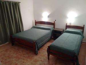 two beds in a room with green sheets at Hotel Las Moras in La Rioja
