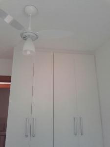 a ceiling fan and white cabinets in a kitchen at Condominio Mar de Gales in Macaé