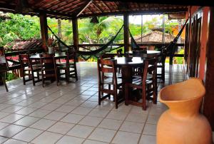a restaurant with wooden tables and chairs and a table and a vase at Hotel Pousada Marambaia in Arraial d'Ajuda