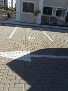 a shadow of a building on a brick street at Condominio Mar de Gales in Macaé