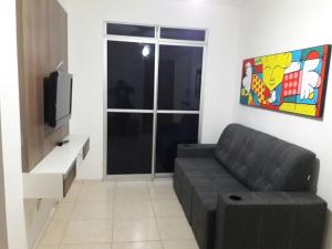 a living room with a couch and a tv at Condominio Mar de Gales in Macaé