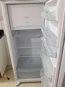 an empty refrigerator with its door open in a kitchen at Condominio Mar de Gales in Macaé