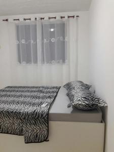 a bed in a bedroom with a zebra blanket and a window at Condominio Mar de Gales in Macaé