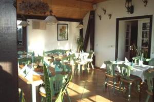 uma sala de jantar com cadeiras verdes e mesas num restaurante em Hotel Gasthof zur Linde em Weißbach