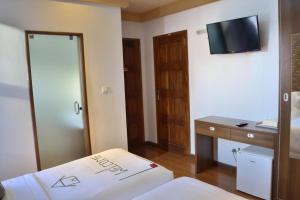 Habitación de hotel con cama, escritorio y TV. en Turquoise Residence by UI en Hulhumale