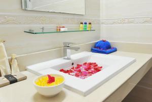 un lavandino in bagno con una ciotola di fiori di Turquoise Residence by UI a Hulhumale