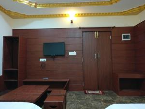 a room with a door and a tv on a wall at The Shades Holiday inn in Kushālnagar