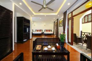 a living room with a ceiling fan and a table at Little Town Villa in Hoi An