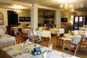 a dining room with white tables and chairs and chandeliers at Klein Waterval Riverside Lodge in Franschhoek