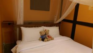 due orsacchiotti seduti sopra un letto di PianoPiano B&B a Jincheng
