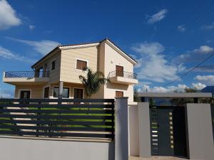 a house behind a white fence with a gate at Dimitris Villa in Aigio