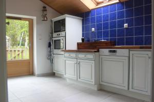 una cucina con armadi bianchi e una parete piastrellata blu di les gites du grenit a La Chapelle-Neuve