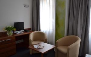 ein Hotelzimmer mit 2 Stühlen, einem Schreibtisch und einem TV in der Unterkunft Lipno-Apartmán Frymburk D110 in Frymburk