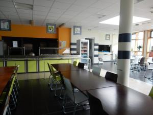 a cafeteria with tables and chairs and a kitchen at Auberge de jeunesse L'Escale in Dunkerque
