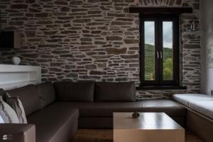 ein Wohnzimmer mit Sofa und Ziegelwand in der Unterkunft Stone Villa Pelion in Áfissos