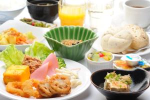una mesa blanca con platos de comida. en Hotel Route-Inn Shinonoi, en Nagano