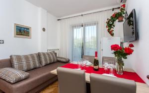 ein Wohnzimmer mit einem Tisch mit Weingläsern und einer Couch in der Unterkunft Apartments Lucija in Baška