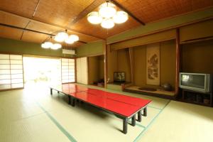 Zimmer mit einem roten Tisch in einem Zimmer mit einem TV in der Unterkunft Wakariki Ryokan in Yanagawa